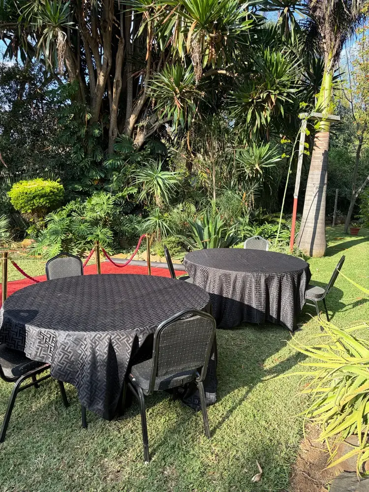 Round tables with black patterned linen and black banquet chairs